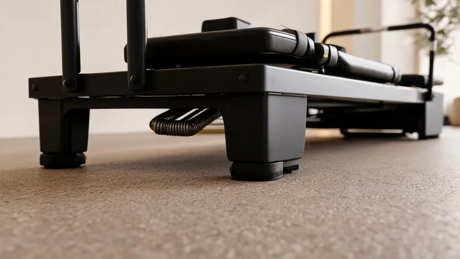 Pilates studio flooring: best surfaces for your reformers 1 Close-up of k30 reformer feet and non-slip pads on a rubber pilates studio floor